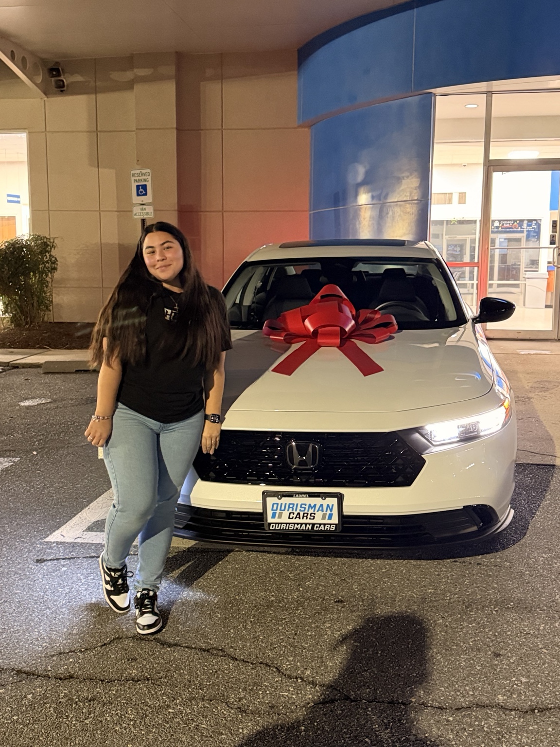 Customer celebrating beside a white Honda with a red bow at night