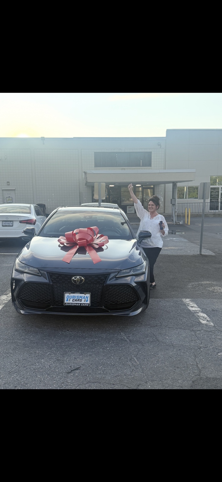 Customer celebrating beside a Toyota with a red bow