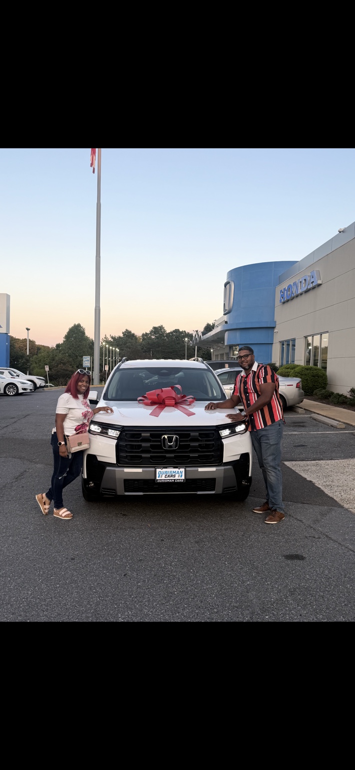 Two customers beside a white Honda SUV with a red bow