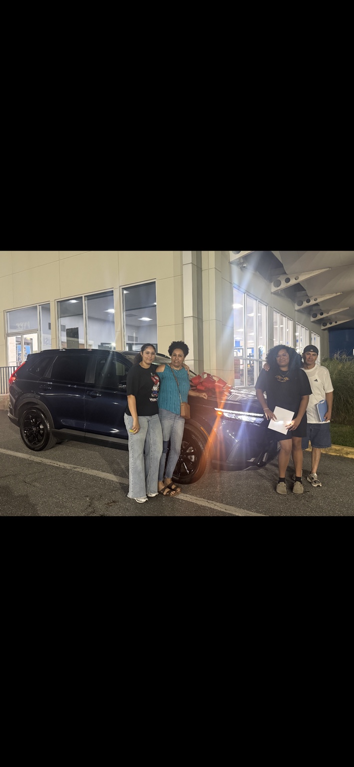 Group of customers beside a dark SUV with a red bow