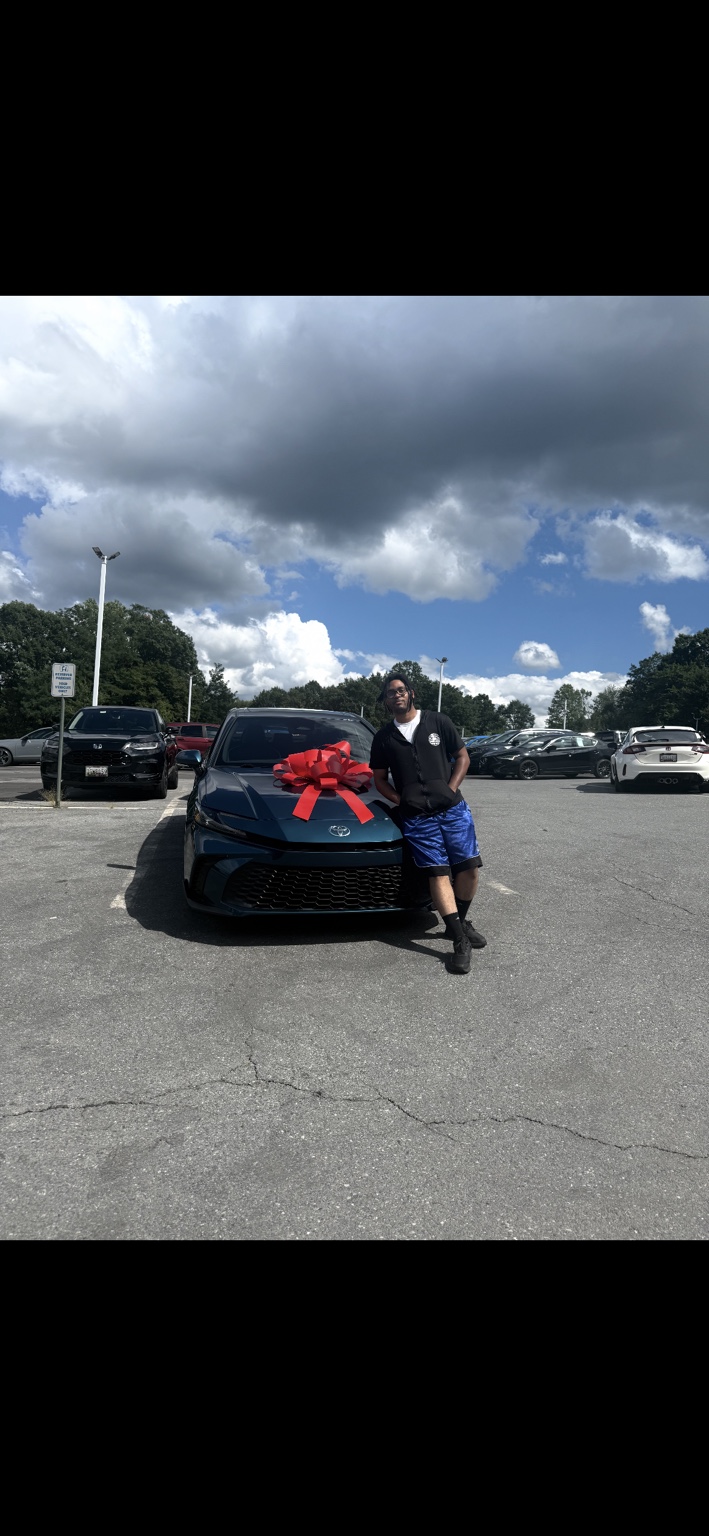 Customer beside a Toyota sedan with a red bow