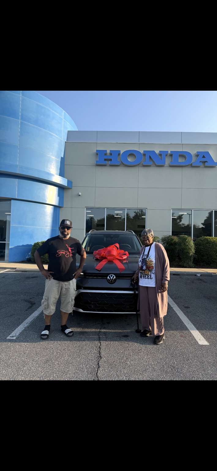 Two customers beside a Volkswagen SUV with a red bow