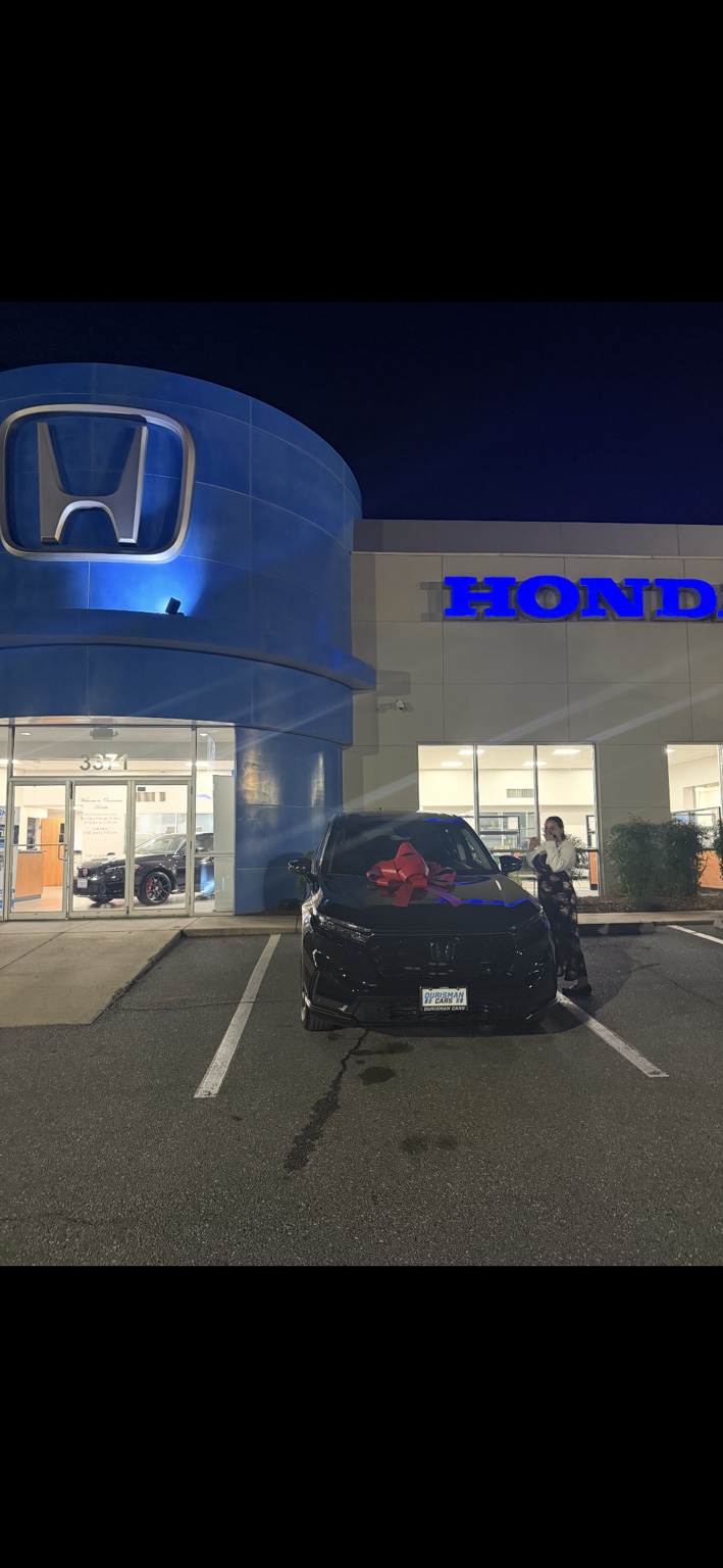 Customer beside a dark SUV with a red bow at night