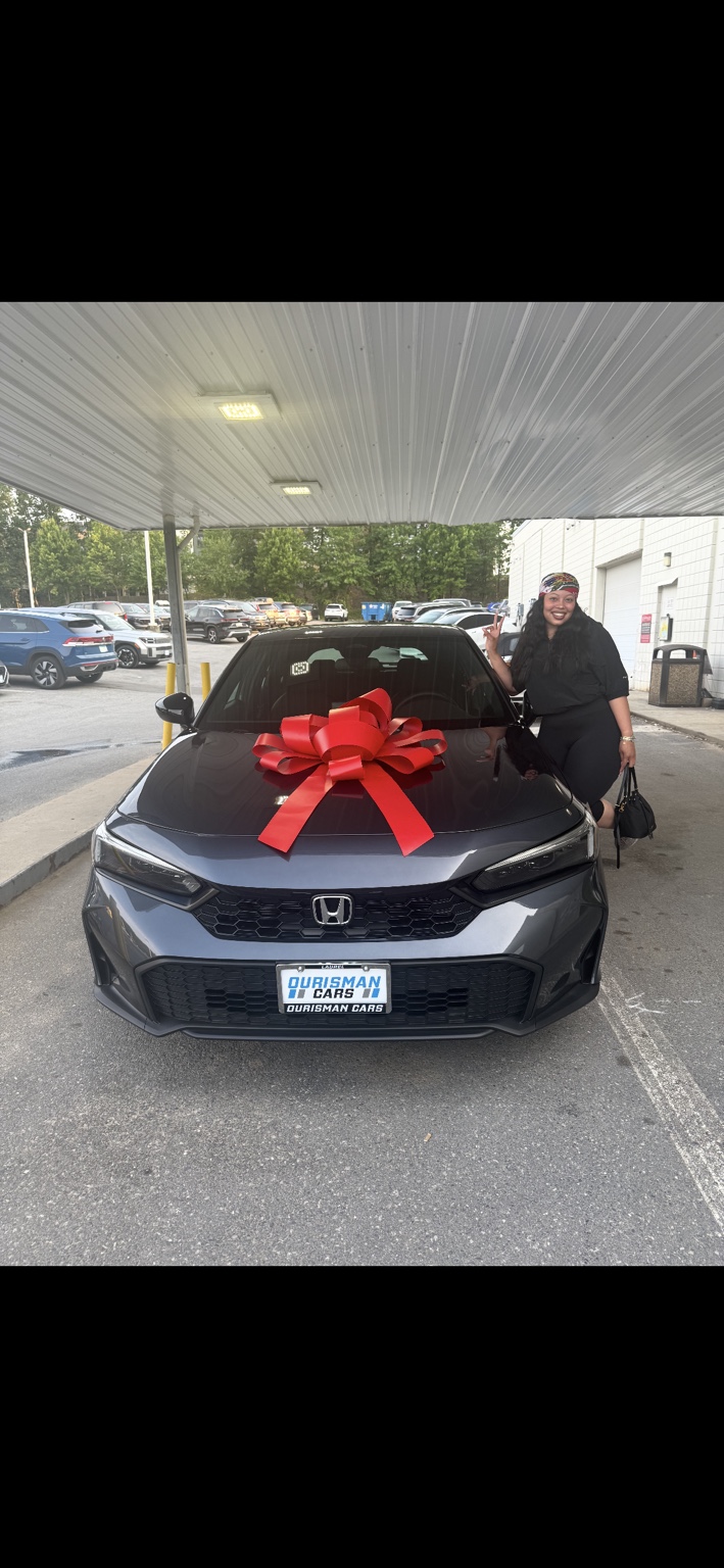 Customer beside a gray Honda sedan with a red bow