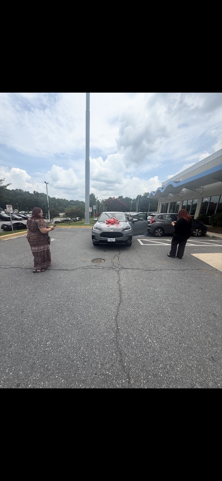 Customers beside a silver Honda SUV with a red bow