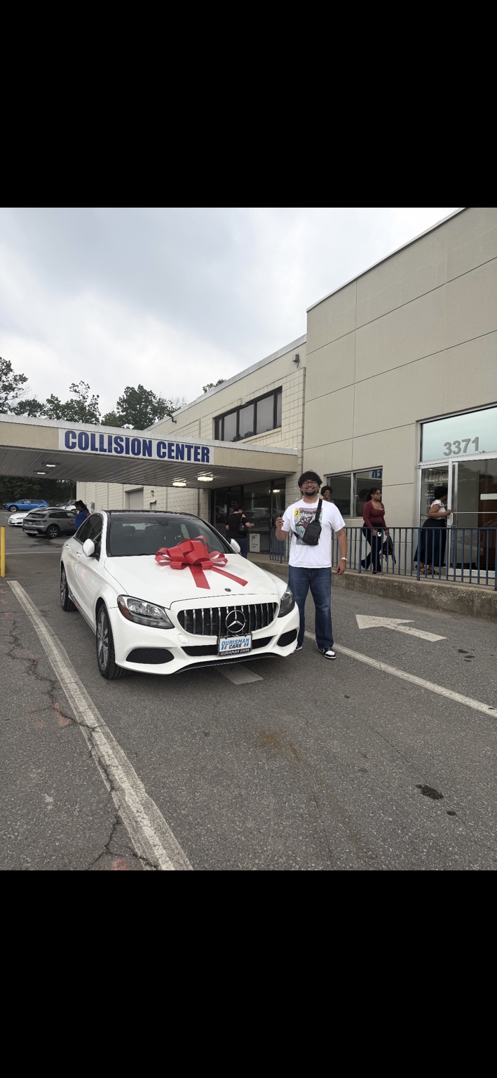 Customer beside a white Mercedes sedan with a red bow