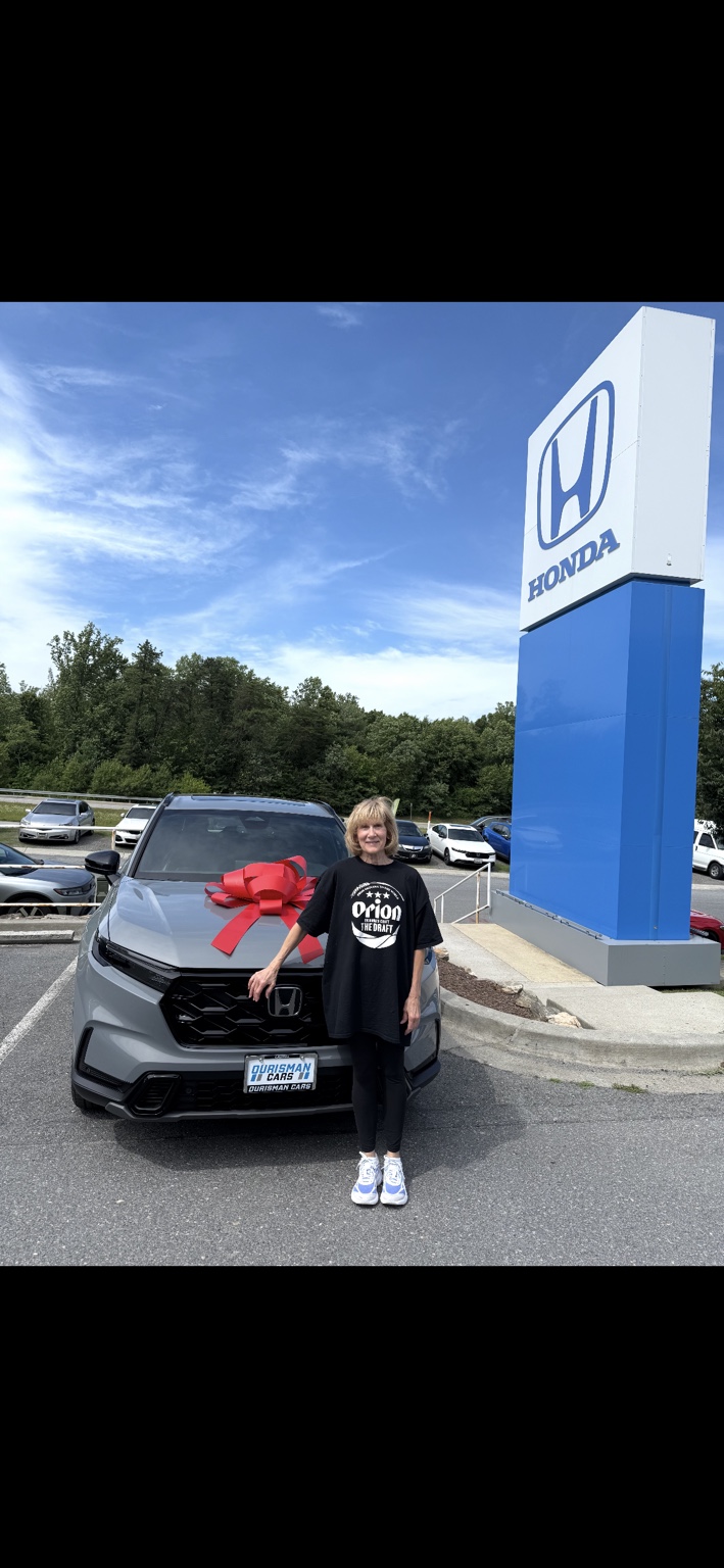 Customer beside a gray Honda SUV with a red bow