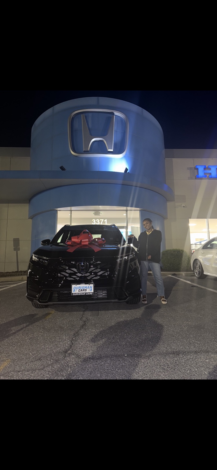 Customer beside a dark Honda SUV with a red bow at night
