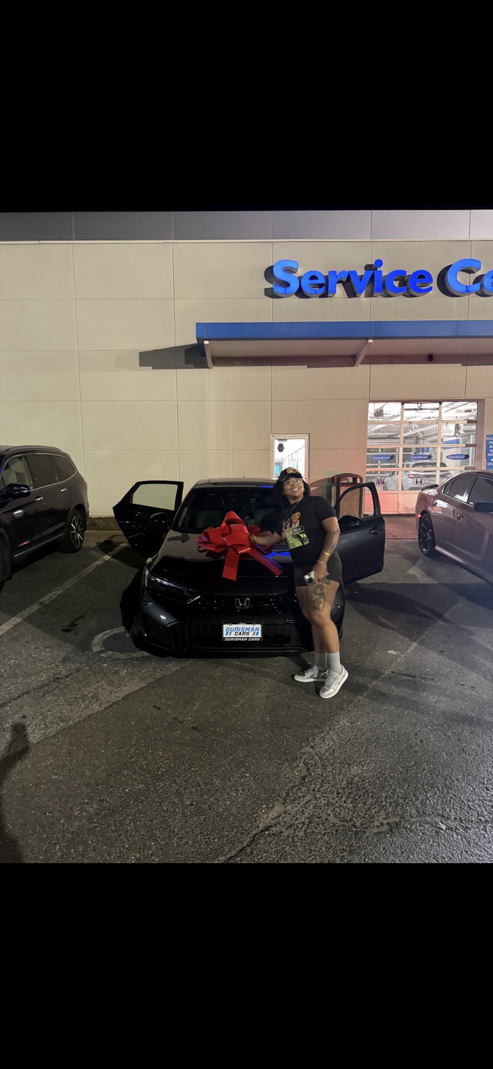 Customer beside a dark Honda sedan with a red bow at night