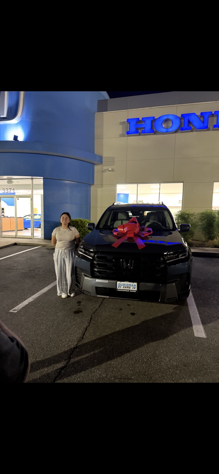 Customer beside a dark Honda SUV with a red bow at night