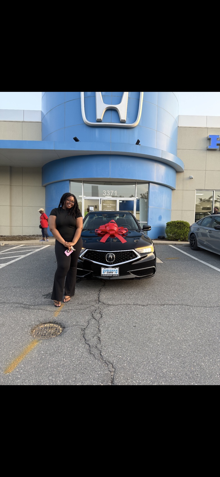 Customer beside a black Acura sedan with a red bow
