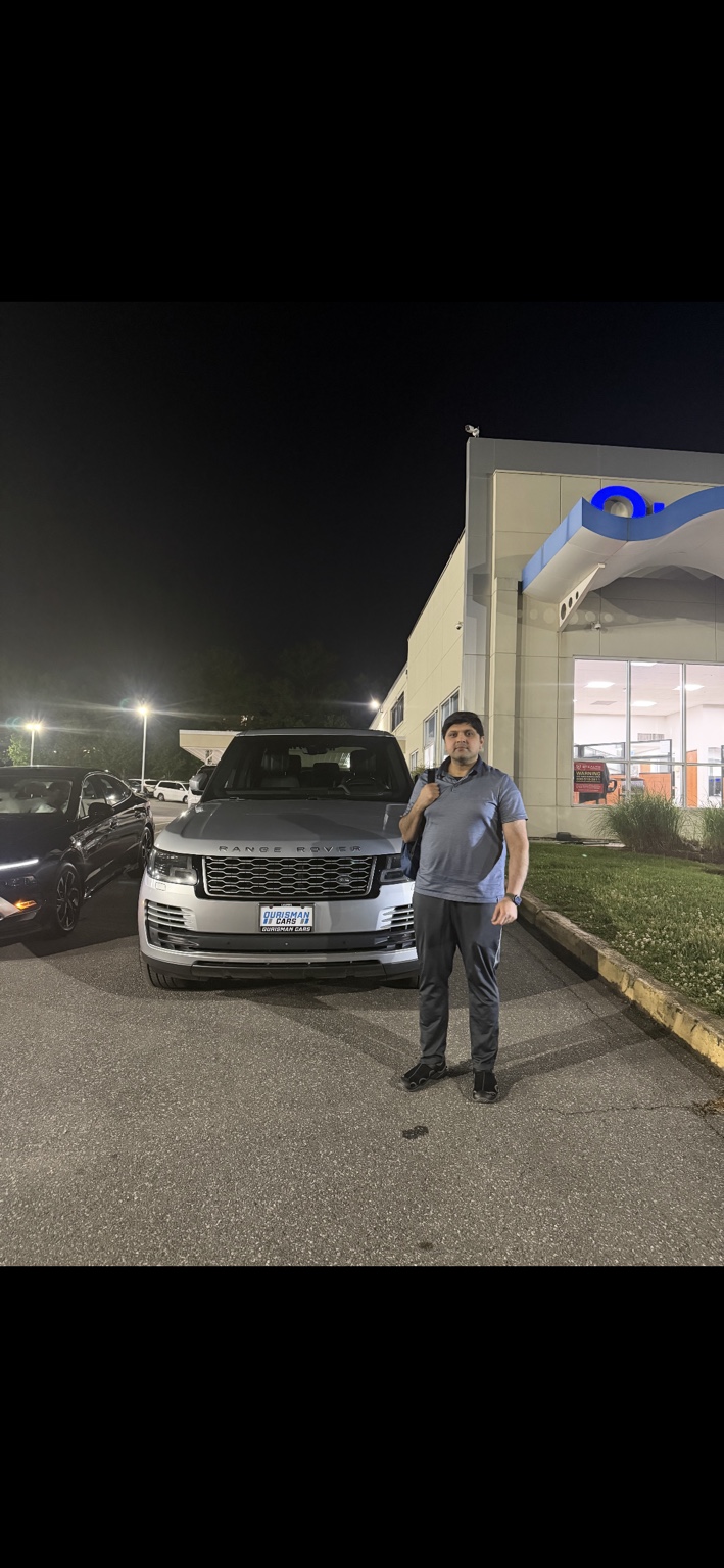Customer beside a silver Range Rover at night