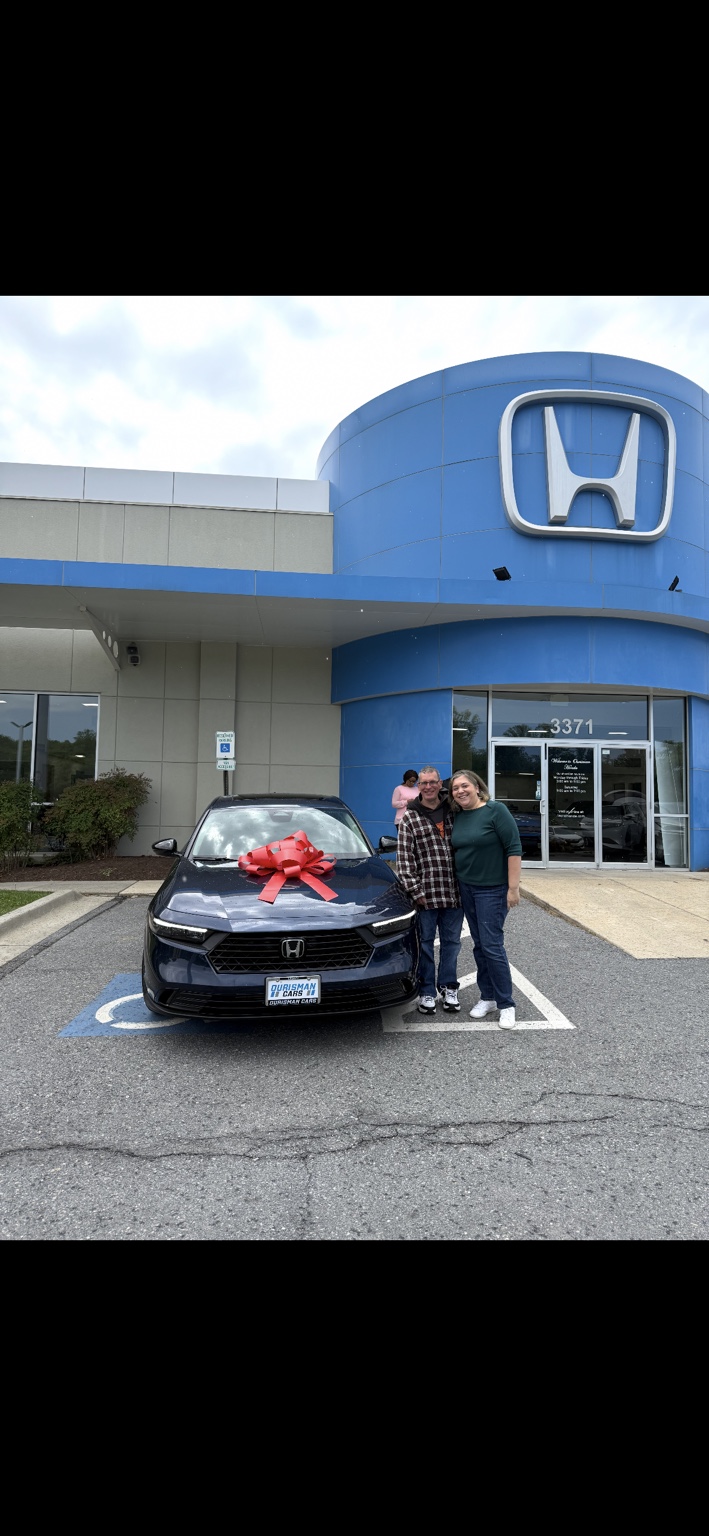 Two customers beside a dark Honda sedan with a red bow