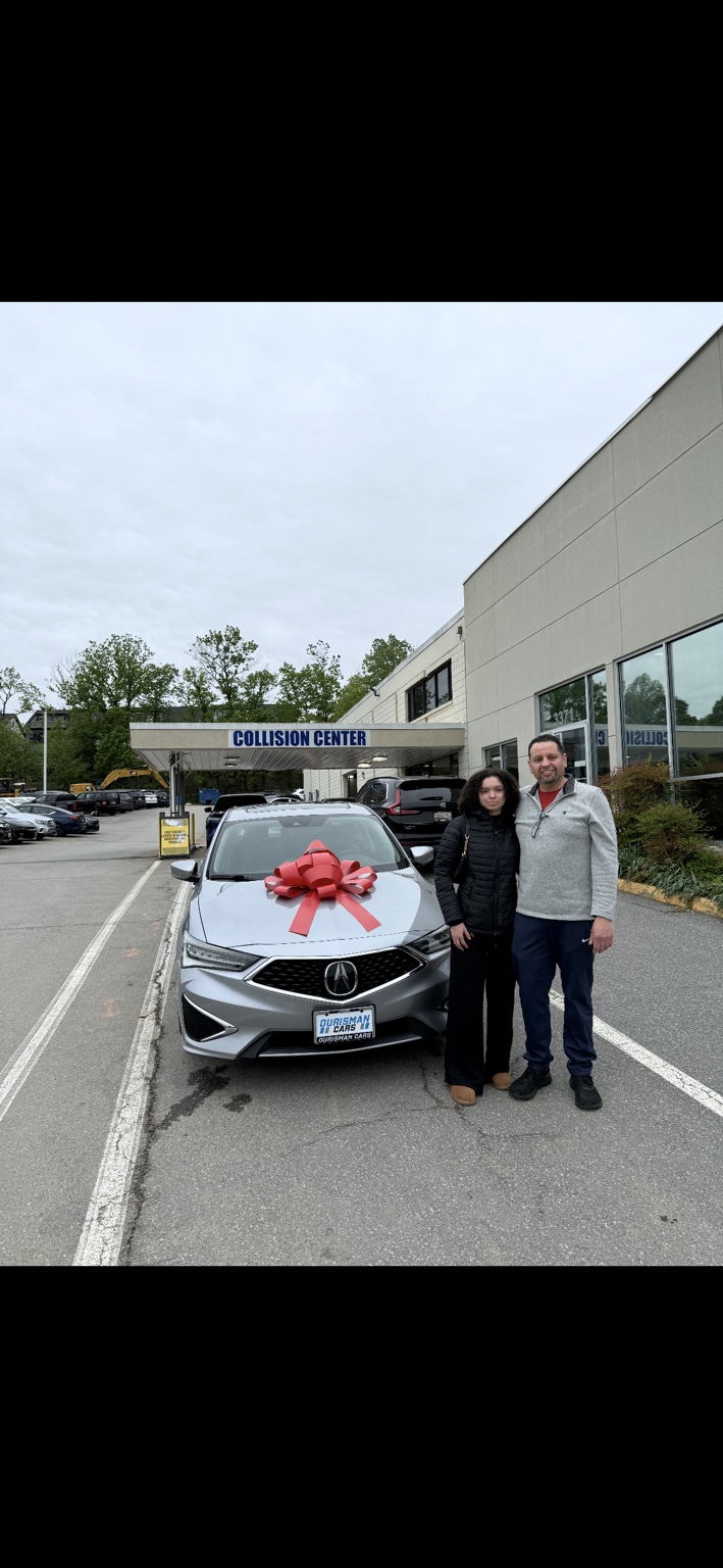Two customers beside a silver Acura sedan with a red bow