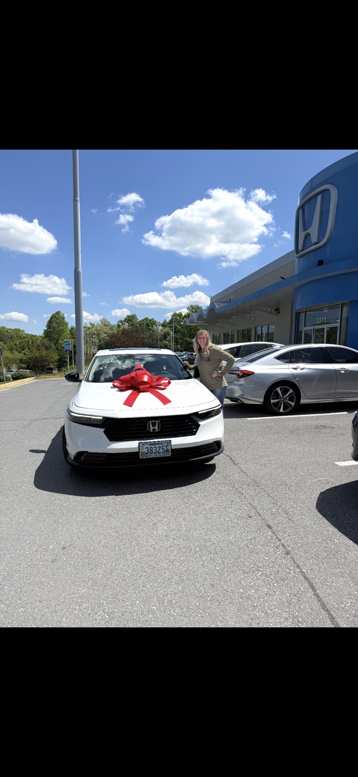 Customer beside a white Honda sedan with a red bow