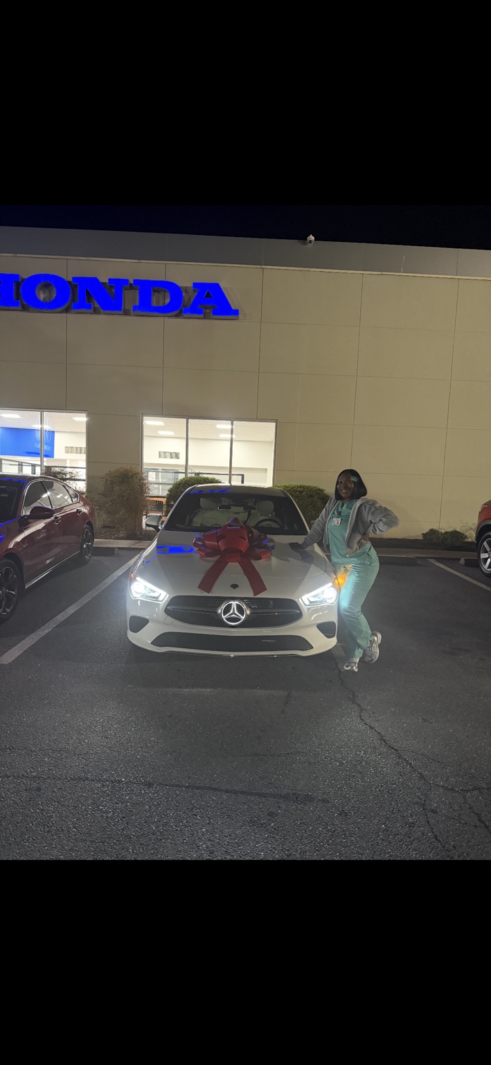 Customer beside a white Mercedes sedan with a red bow at night