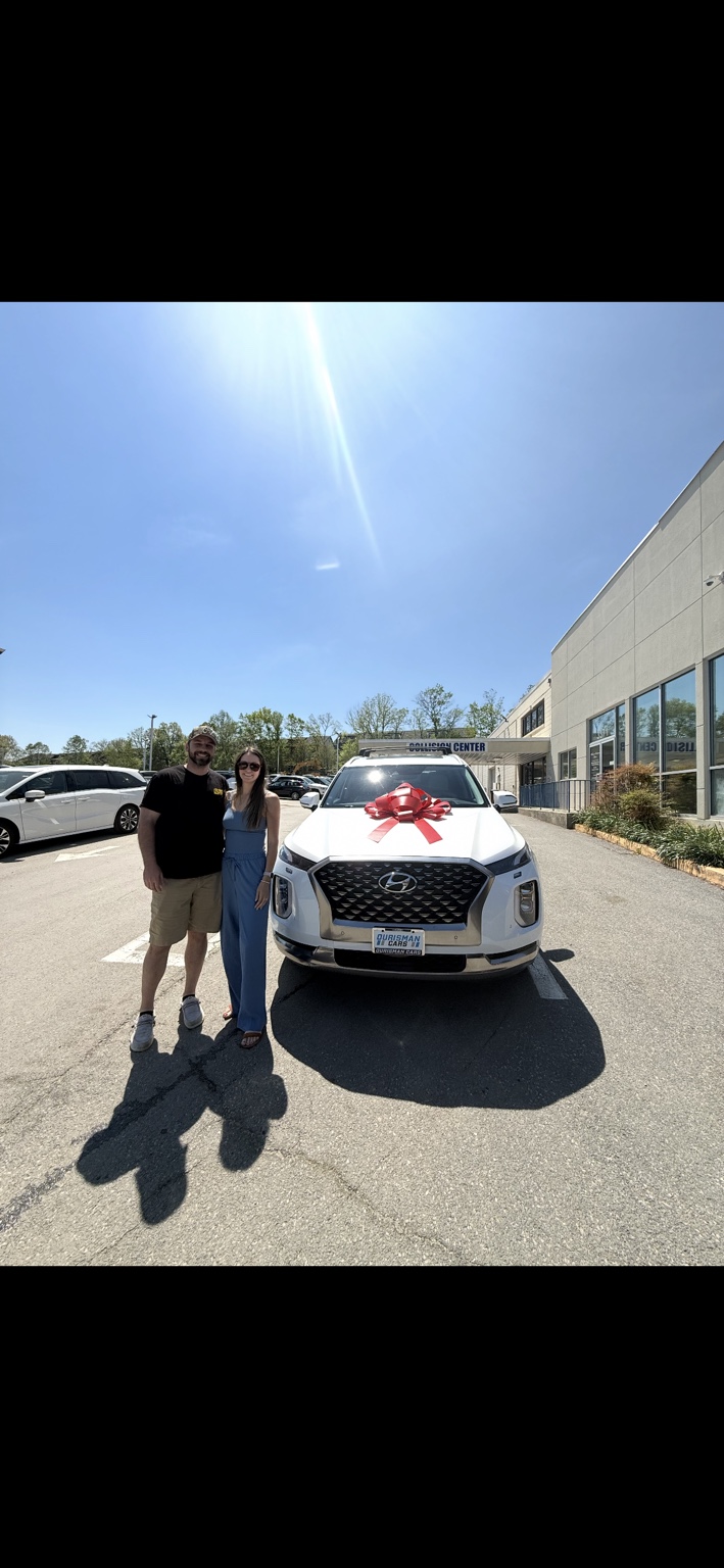 Two customers beside a white Hyundai SUV with a red bow