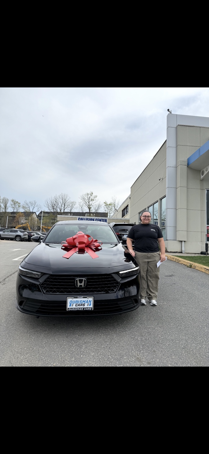 Customer beside a black Honda sedan with a red bow