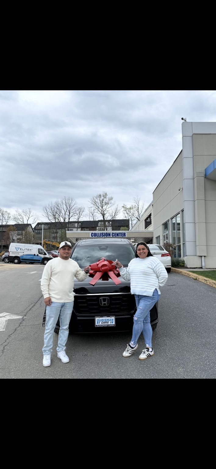 Two customers beside a black Honda SUV with a red bow