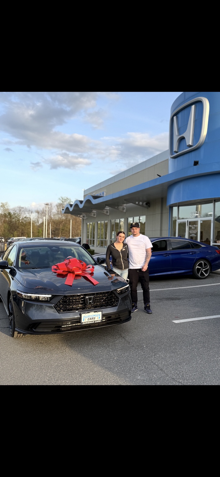 Two customers beside a dark Honda sedan with a red bow