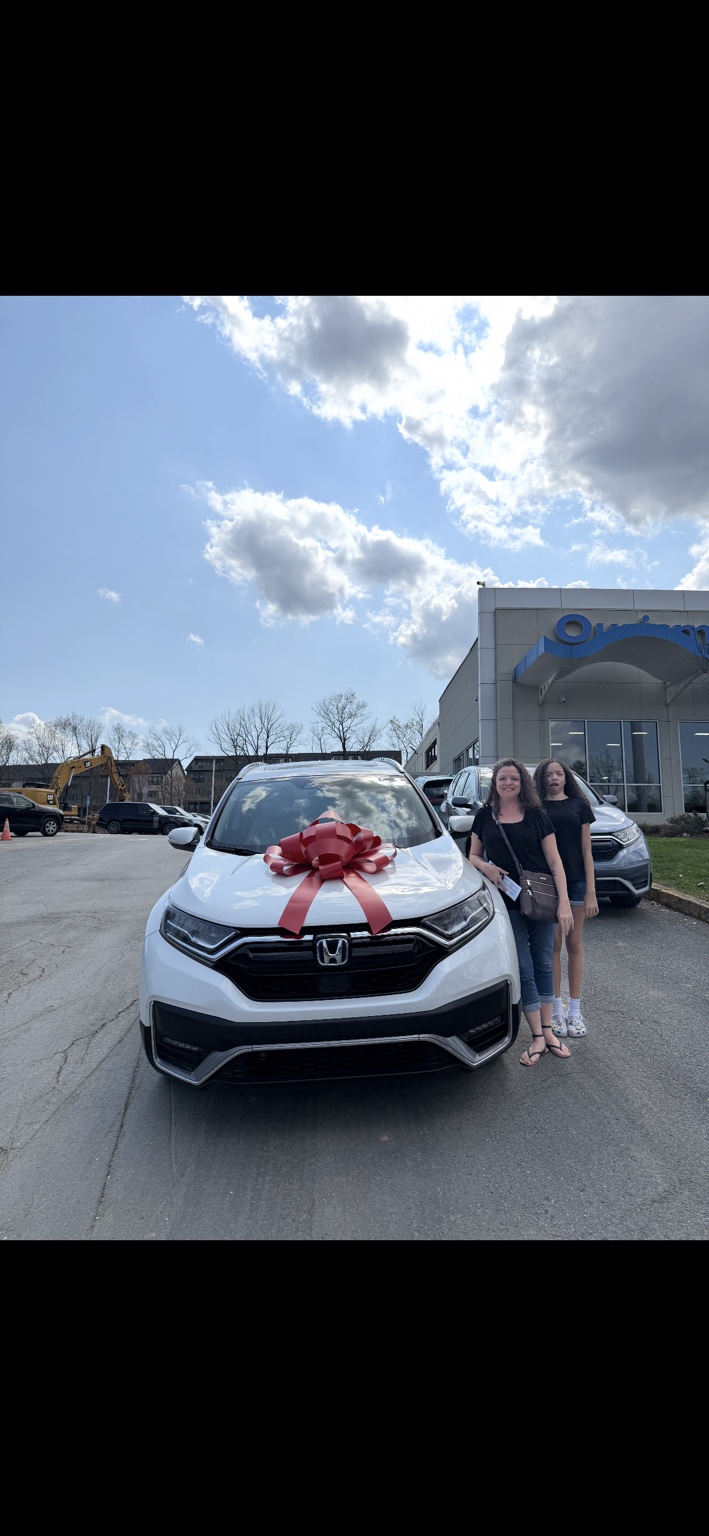 Two customers beside a white Honda SUV with a red bow