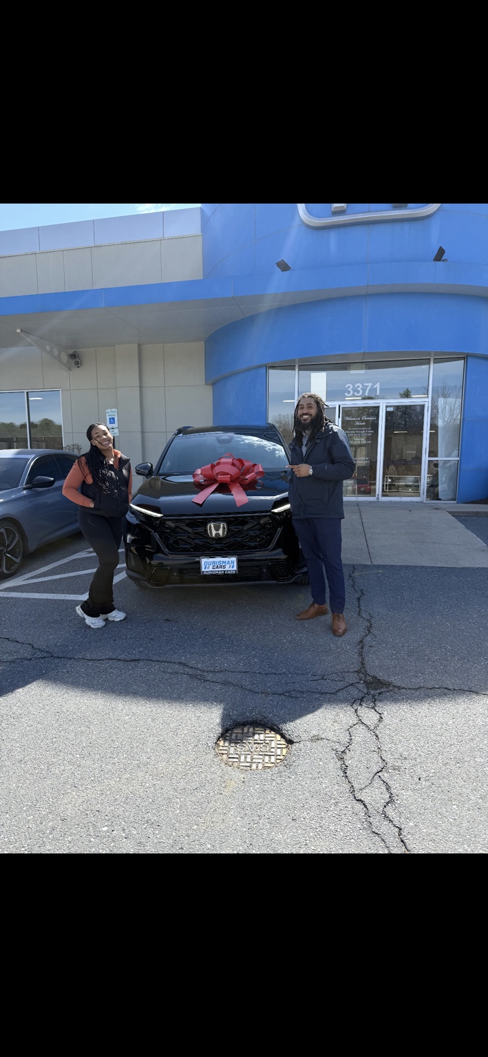 Customer and Jamel beside a black Honda with a red bow