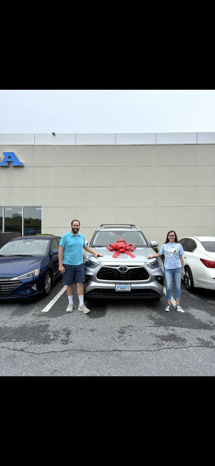 Two customers beside a silver Toyota SUV with a red bow